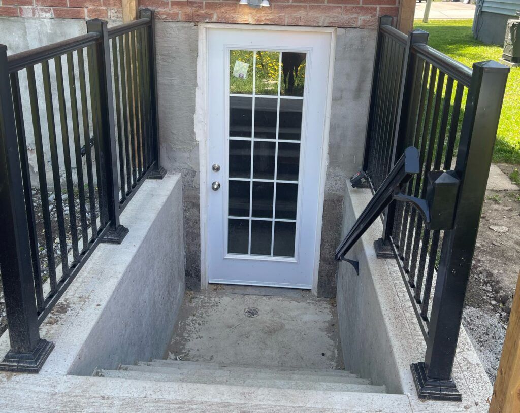 Best Construction Company in GTA offers Basement side entrance with secure door and well-lit concrete steps leading to the outside, providing easy access and added functionality to the home. 